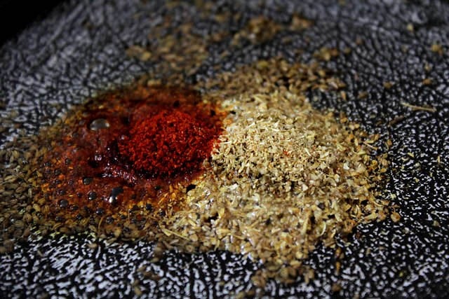 red chili powder and coriander powder added to the hot oil in the pan. 