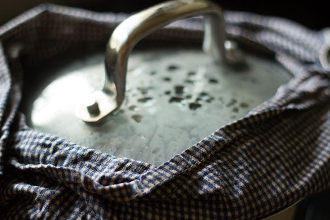 pot covered with glass lid covered with a moistened kitchen napkin