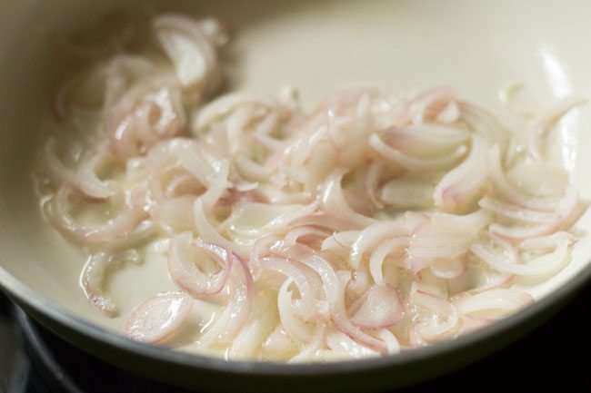 sliced onions in oil in white pan