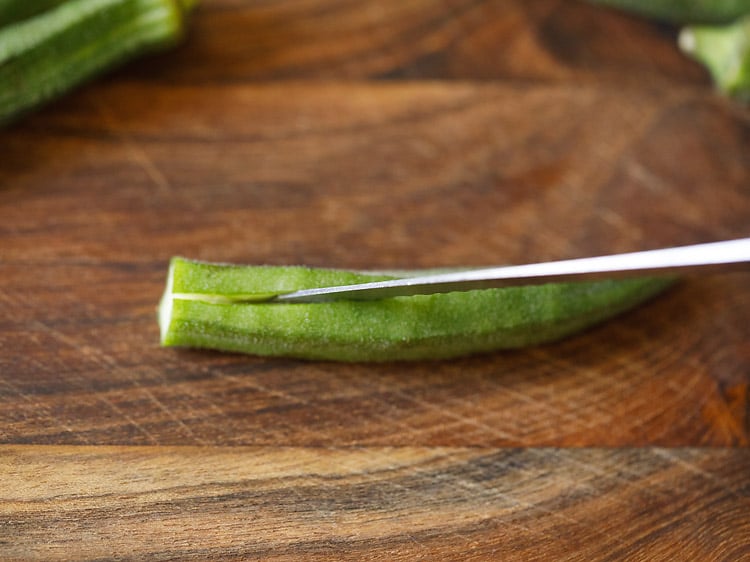 slicing bhindi without cutting into 2 parts.