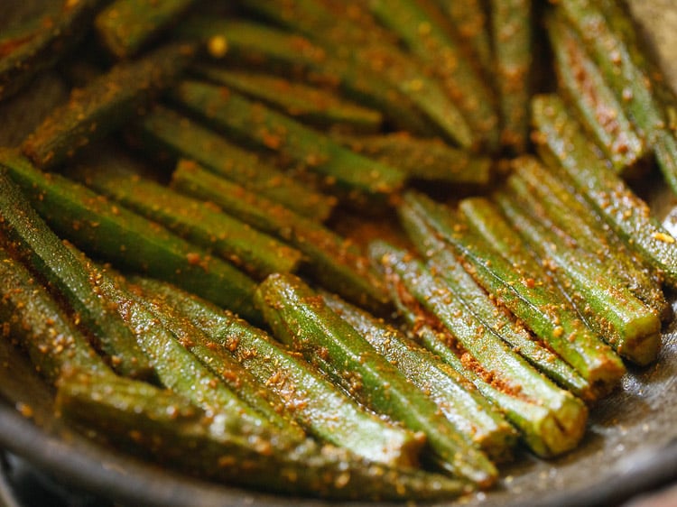 stir occasionally and slow cooking bharwa bhindi in the kadai