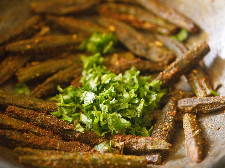 adding coriander leaves to cooked bharwa bhindi