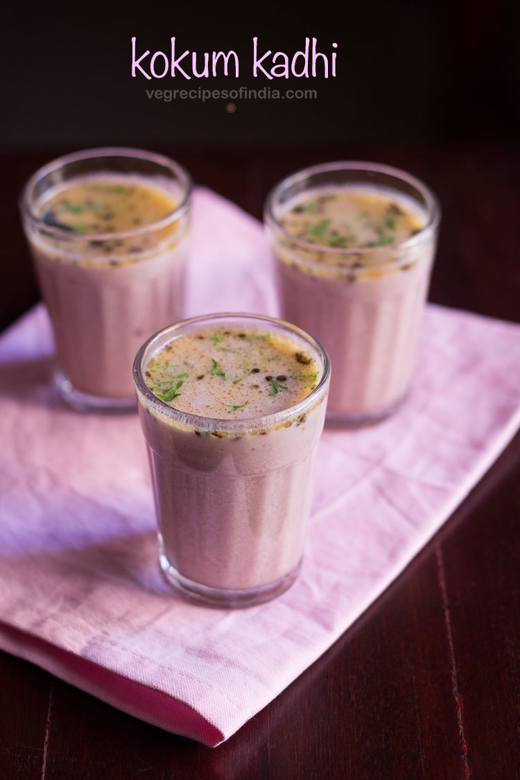 three clear glasses of kokum kadhi on a pink napkin.