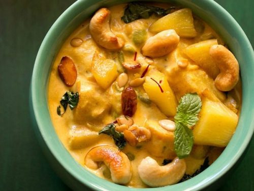 navratan korma garnished with coriander leaves and served in a green bowl.