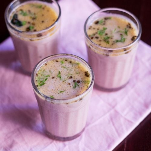 three clear glasses of kokum kadhi on a pink napkin.