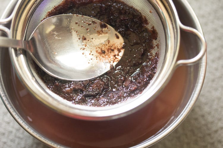 pressing kokum pulp with the back of a spoon through a mesh strainer to get all of the sour extract.