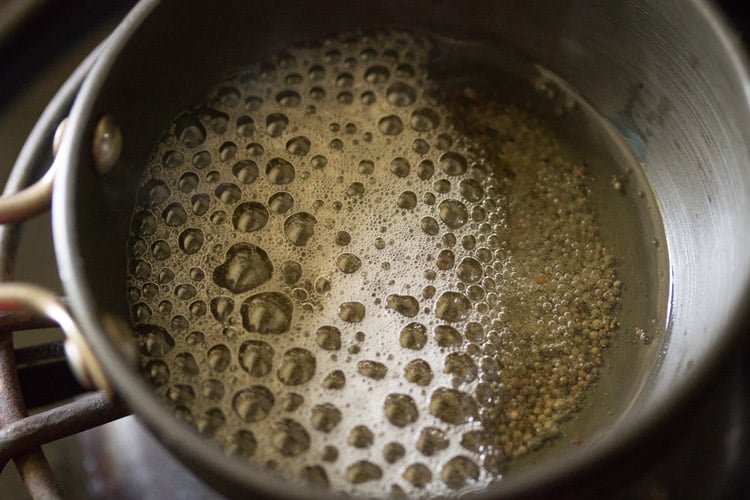 mustard seeds crackling in oil for making solkadi recipe.