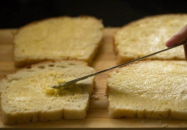 spreading room temperature butter on bread slices.