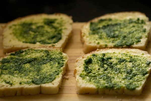 prepared coriander chutney spread on bread slices for bombay sandwich. 