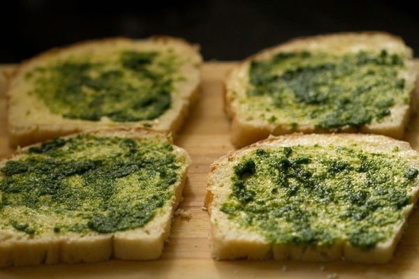 prepared coriander chutney spread on bread slices for bombay sandwich.