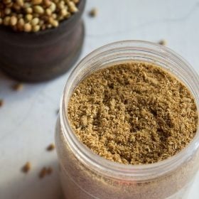 coriander powder in a jar on a white board