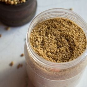 coriander powder in a jar on a white board