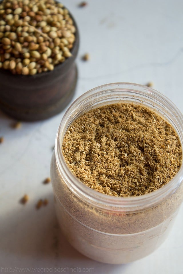 coriander powder in a jar on a white board