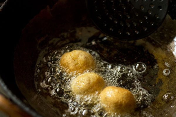 lightly fried falafel being turned over in hot oil