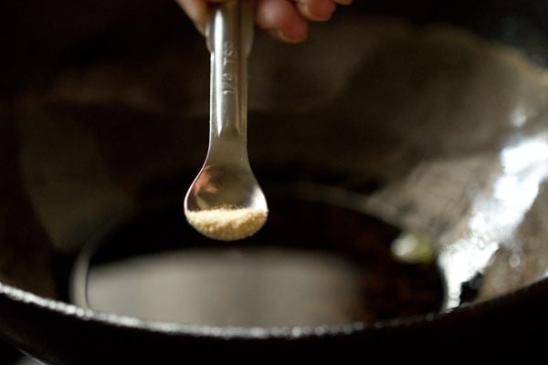 adding asafoetida to hot oil in pan.