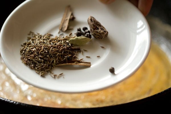 adding whole spices to pan.