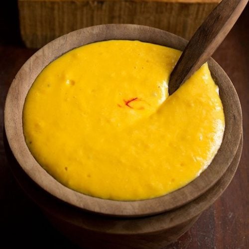 mango shrikhand in a wooden bowl with wooden spoon inside