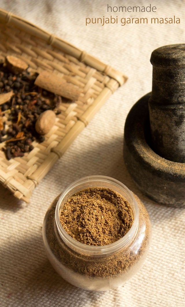 homemade punjabi garam masala in a jar on a cream jute fabric.