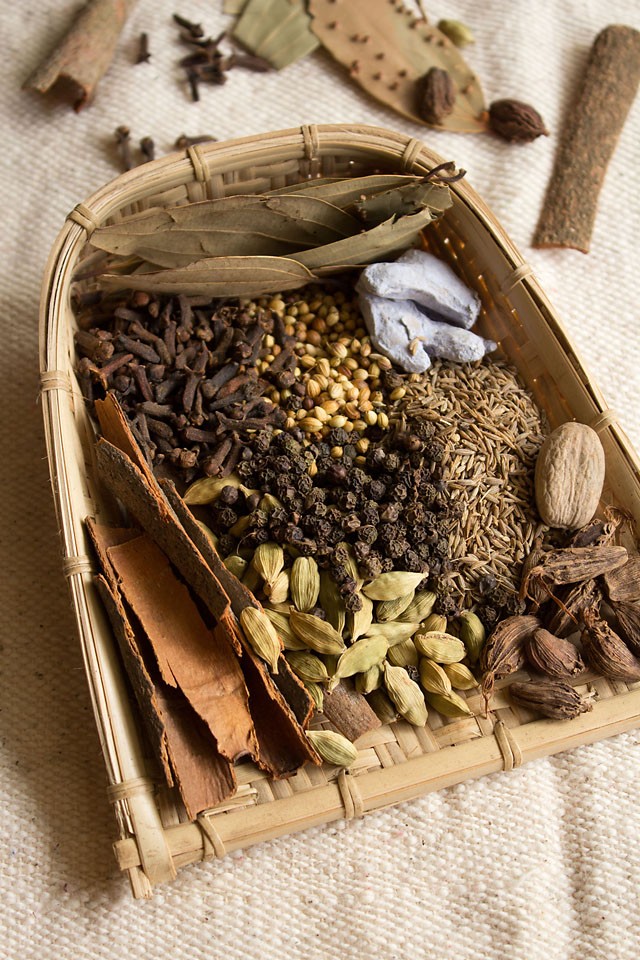 whole spices for Punjabi garam masala on a woven tray.