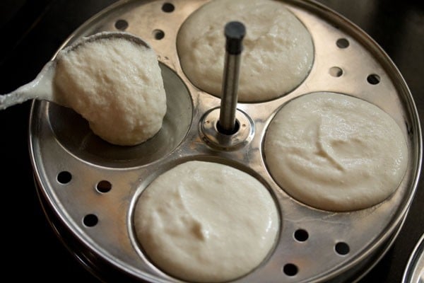 adding idli batter to idli moulds