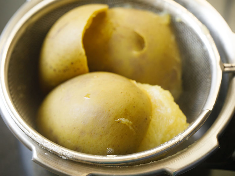 straining the cooked mangoes through a mesh strainer.