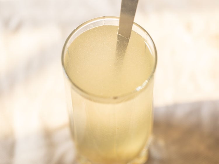 stirring concentrate and water together to make aam panna drink.