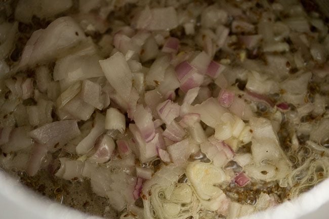 adding onions to pot with ajwain.