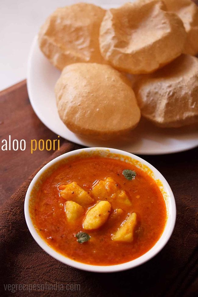 bowl of aloo sabzi with a plate of poori to the side.