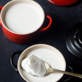 set curd in a red bowl with a spoon filled with curd with text layover.