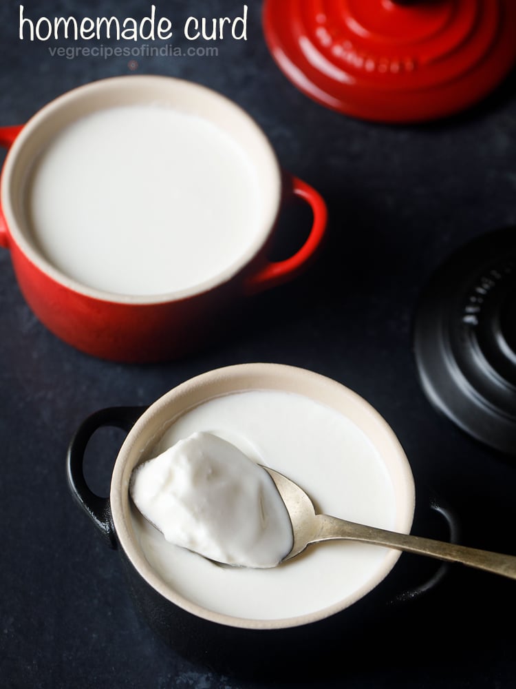 set curd in a red bowl with a spoon filled with curd.