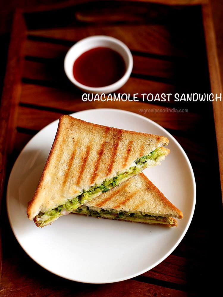 avocado sandwich served on a plate with a side of tomato sauce