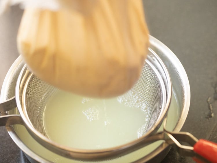 edges of muslin gathered and bundled with whey dripping from the bundle