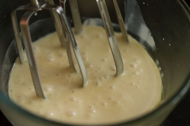 cream being whipped with an electric beater in a glass bowl