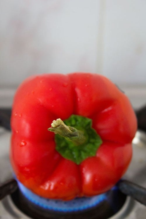roasting a bell pepper over the flame of a gas range.