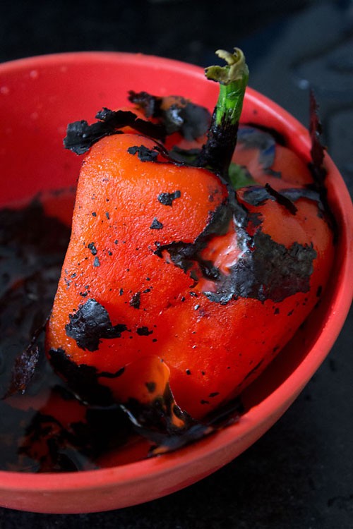 peeling off the charred exterior of the red pepper for making muhammara dip.