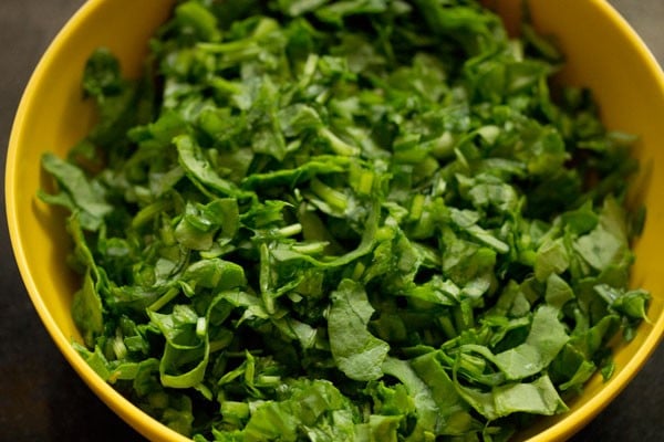 finely chopped spinach in a yellow mixing bowl