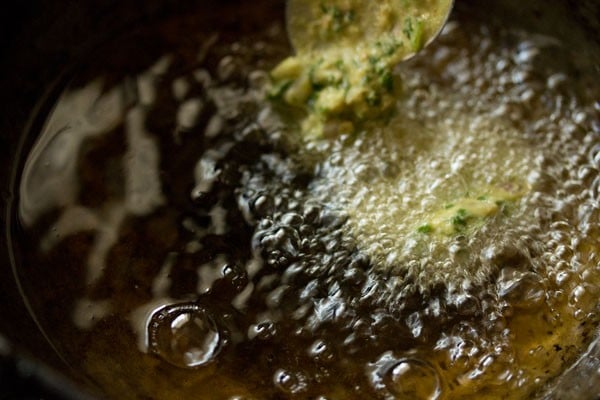 spoonful of batter being dropped in hot oil with a spoon