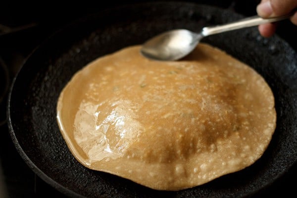 applying ghee on paneer paratha on tawa