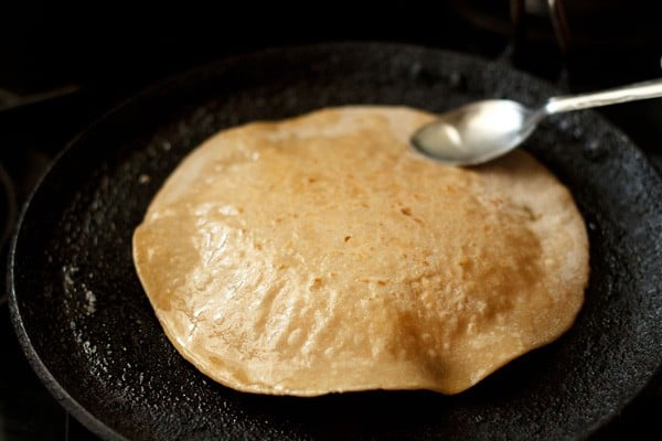 applying ghee on paneer paratha