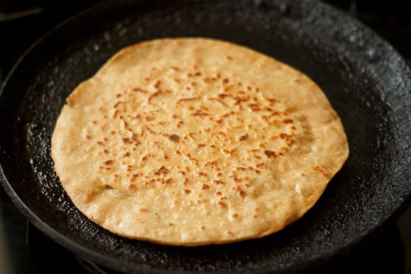 flipping and cooking paneer paratha on tawa