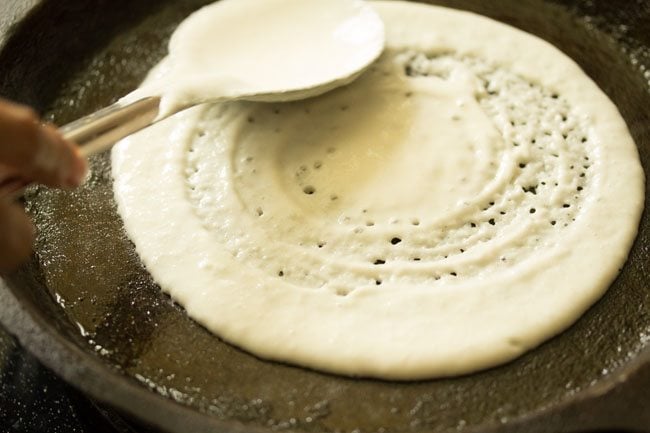 spreading batter on tawa with a spoon