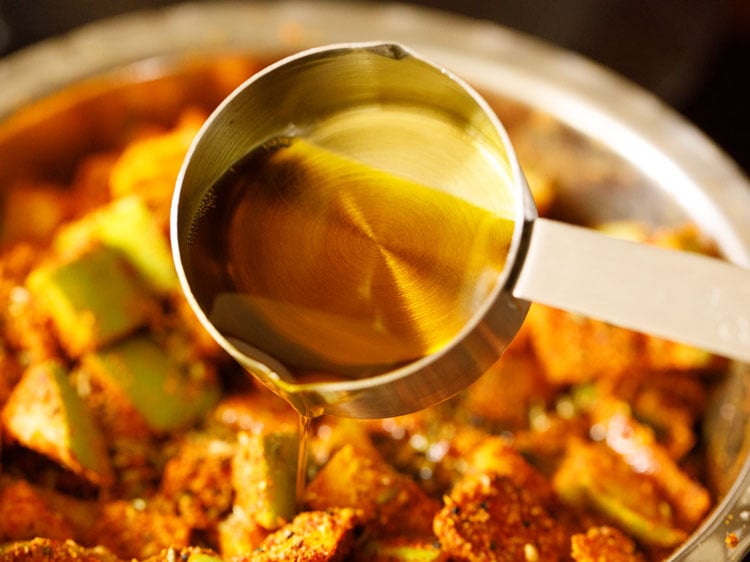 adding mustard oil to the spiced mango pieces 