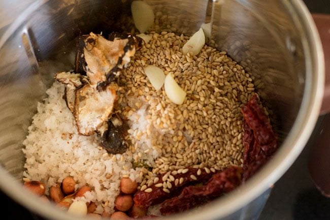 adding roasted peanuts, tamarind, garlic cloves, dried red chilies and salt in blender jar