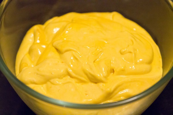 half frozen and slightly molten mango ice cream in a glass bowl