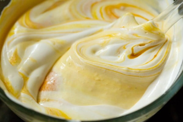  mango pulp and whipped cream being mixed and folded with a spatula
