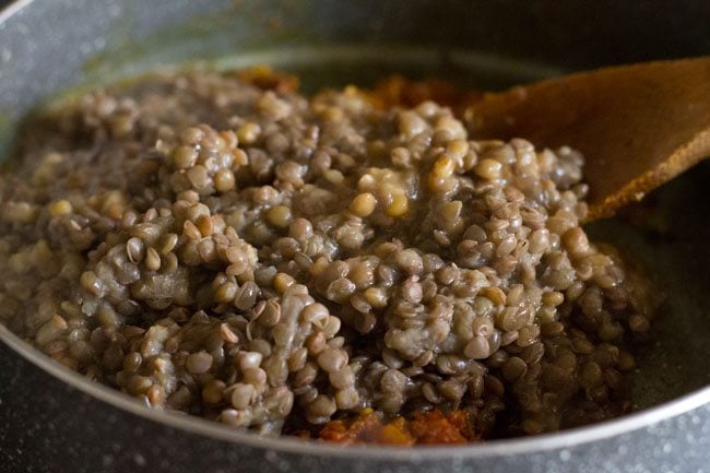 cooked red lentils added to tomato  masala paste for making whole masoor dal. 