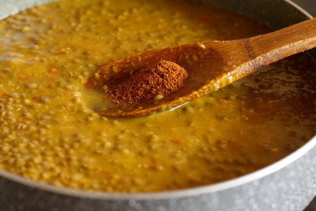 adding garam masala powder to cooked whole masoor dal. 