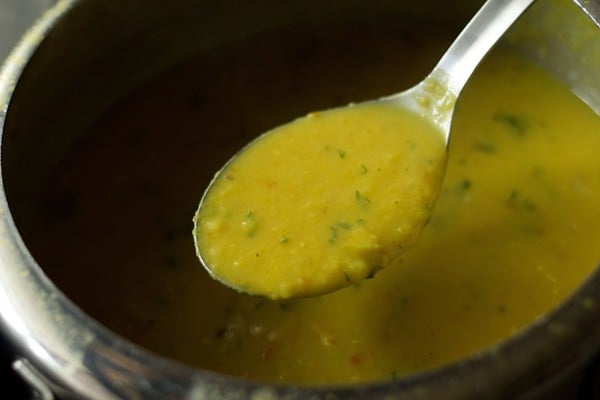 consistency of the lentils or dal being shown with a large spoon