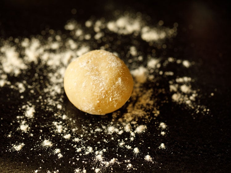 ball of pita bread dough placed on working surface with flour sprinkled all over