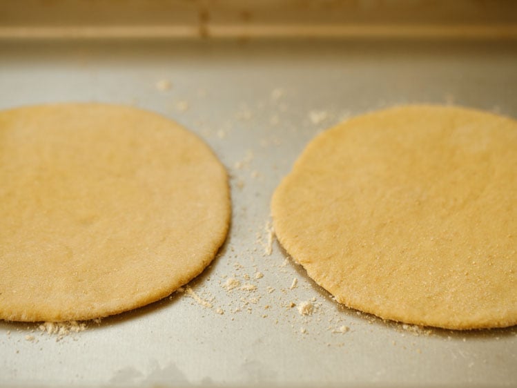 two rolled discs placed in the hot baking tray with some flour already sprinkled on the tray